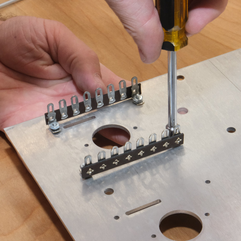 Person using a screwdriver to attach hardware to a Bottlehead amplifier kit chassis plate.