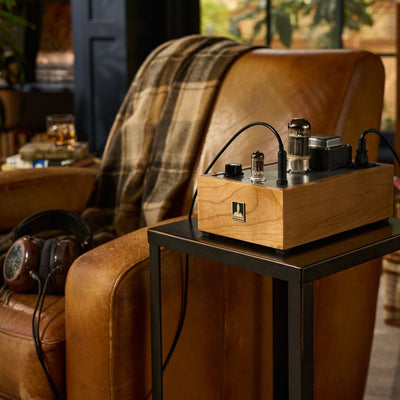 Bottlehead Crack headphone amplifier with headphones and a leather chair.
